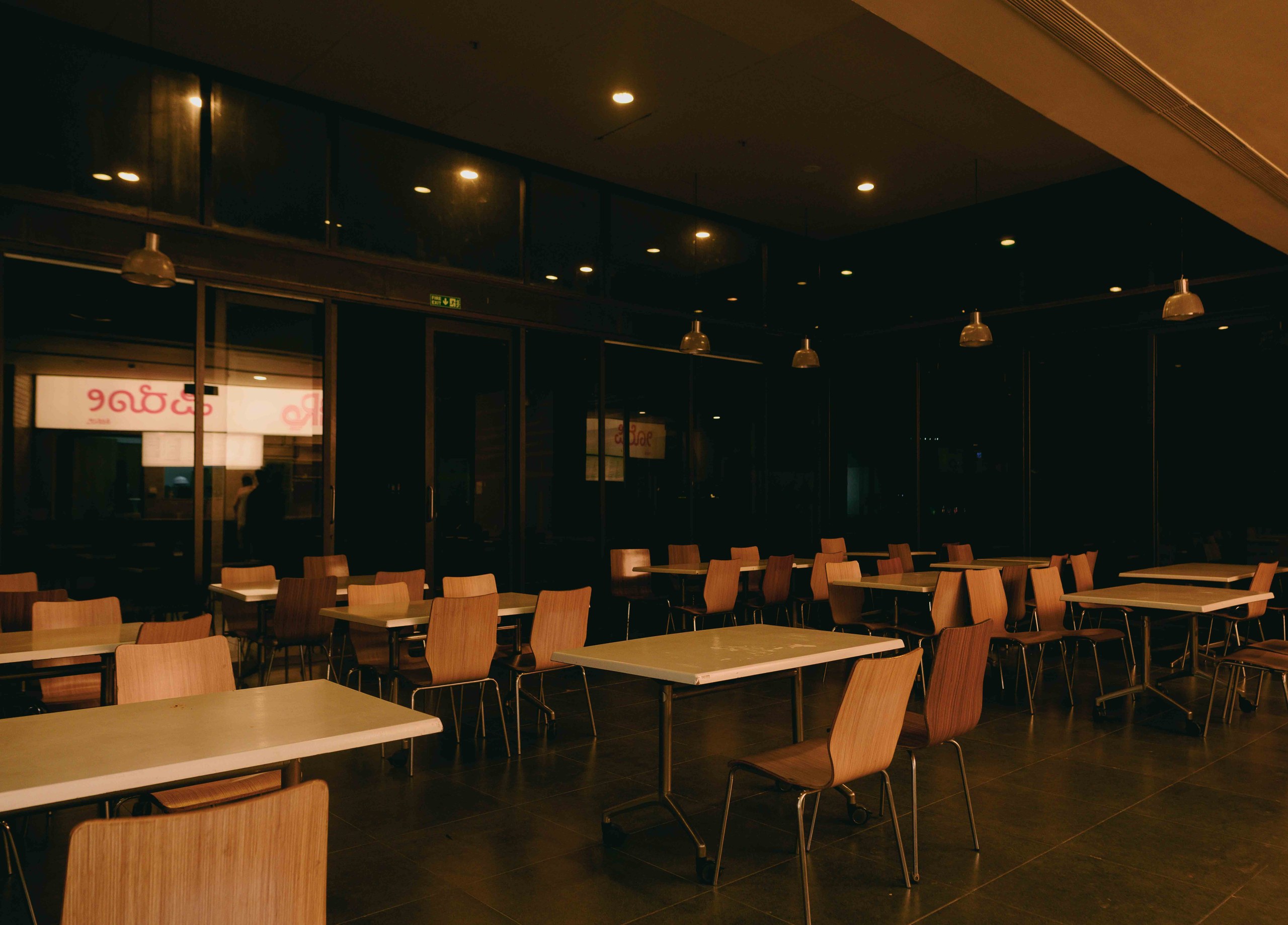 Warm, low-lit PiRo Kitchens diner interior with wooden chairs and tables
